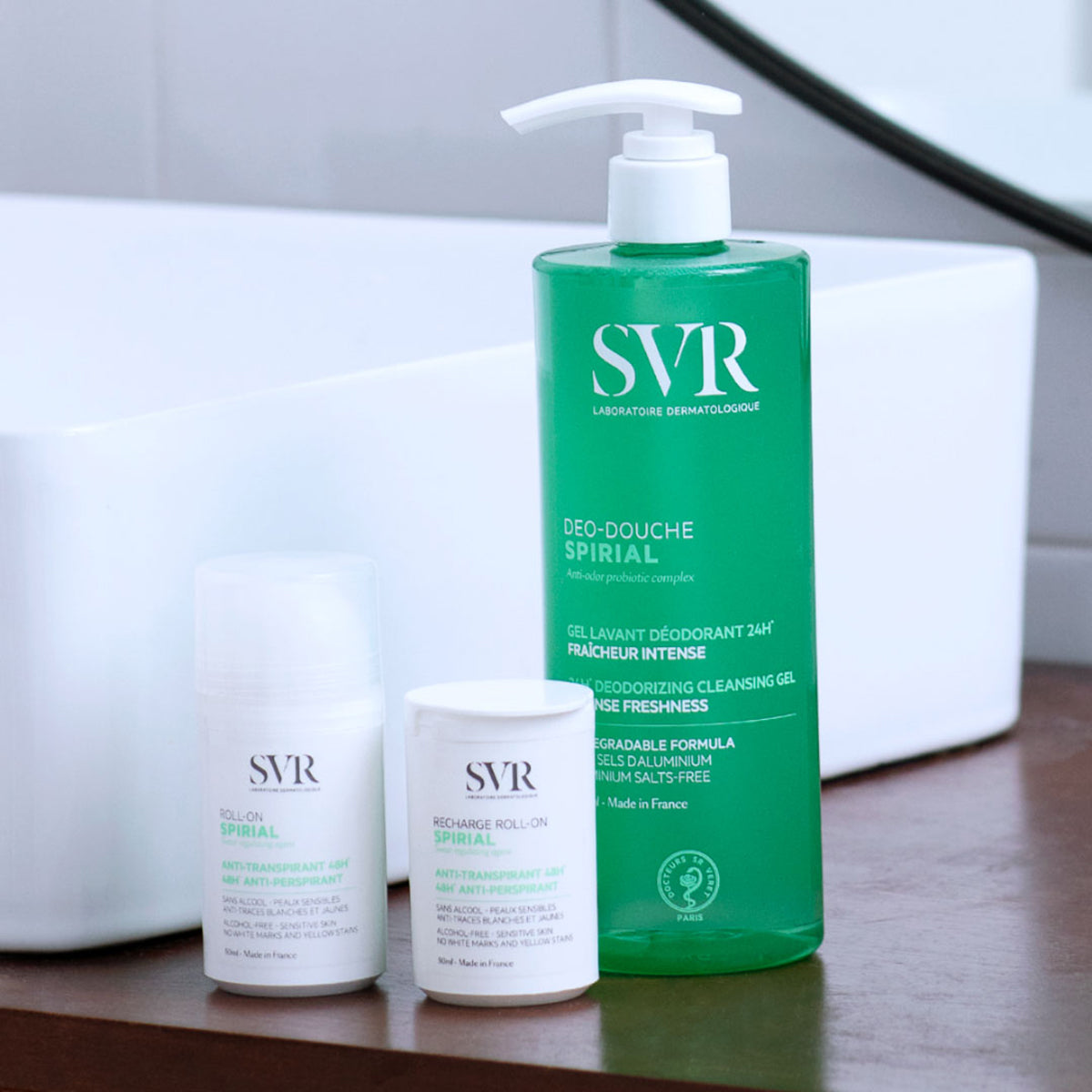 SVR Spirial roll-on, recharge, et gel douche déodorant vert sur un rebord de lavabo blanc.